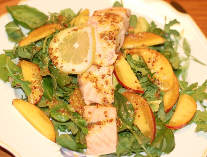 poached salmon salad with peaches poached salmon and peaches on top of a bed of arugula