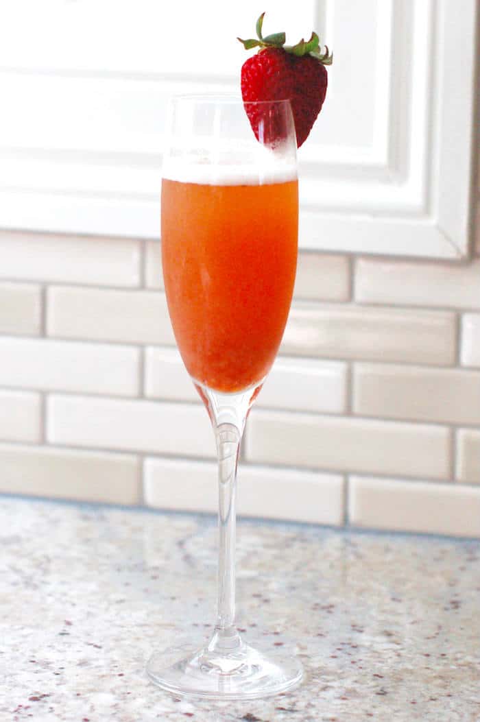 Strawberry Rhubarb Mimosa ready to serve Strawberry Rhubarb Mimosa in Champagne flute with strawberry on rim