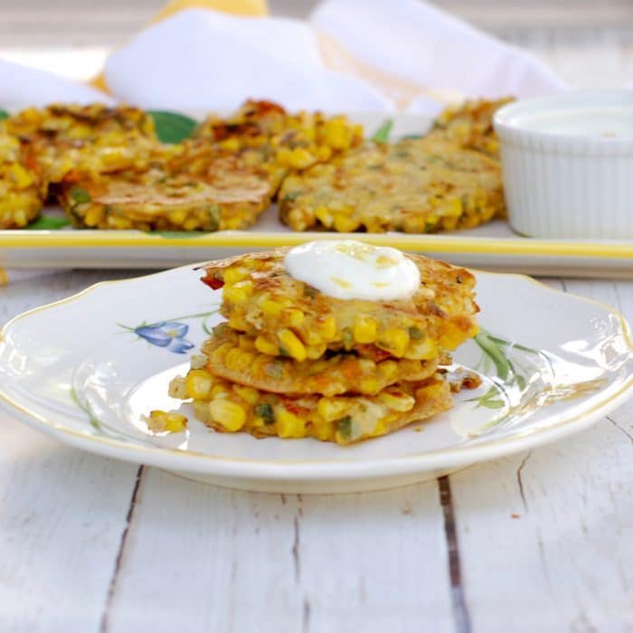 Savory corn & basil cakes are a great vegetarian side dish or main dish. Serve with a light and tangy Lemon Yogurt Sauce. Grill them during the summer or make them inside all year round! Get the vegetarian recipe @jlevinsonrd #summercorncakes #sumersidedishes Corn & Basil Cakes Stacked on Plate