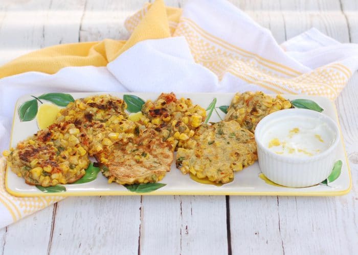 Savory corn & basil cakes are a great vegetarian side dish or main dish. Serve with a light and tangy Lemon Yogurt Sauce. Grill them during the summer or make them inside all year round! Get the vegetarian recipe @jlevinsonrd #summercorncakes #sumersidedishes Corn & Basil Cakes on Tray with Sauce