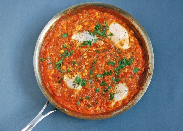 Summer Shakshuka | This summery twist on the classic Israeli breakfast recipe is an easy one-skillet dish of sautéed bell peppers, summer squash, corn, onions, and garlic in a Mediterranean-spiced tomato sauce with poached eggs and feta cheese. Get the gluten-free, vegetarian recipe via JessicaLevinson.com #EasySummerRecipes #ShakshukaRecipe. Summer Shakshuka Recipe in Pan Overhead