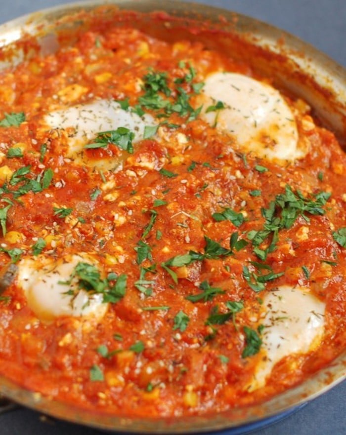 Summer Shakshuka | This summery twist on the classic Israeli breakfast recipe is an easy one-skillet dish of sautéed bell peppers, summer squash, corn, onions, and garlic in a Mediterranean-spiced tomato sauce with poached eggs and feta cheese. Get the gluten-free, vegetarian recipe via JessicaLevinson.com #EasySummerRecipes #ShakshukaRecipe. Summer Shakshuka Recipe in Pan Close Up
