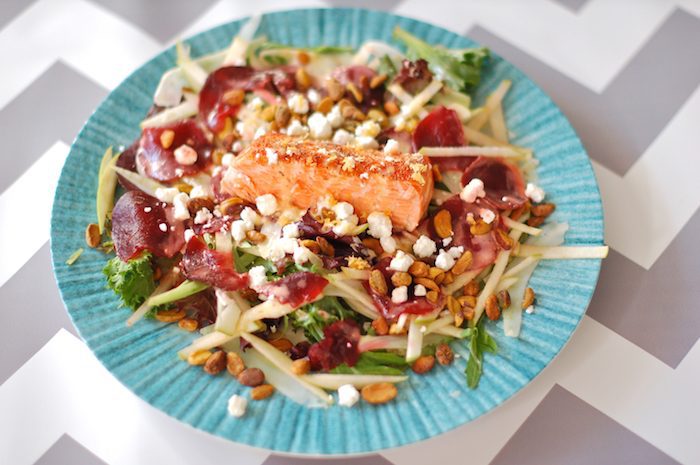 This Salmon Waldorf Salad combines mixed greens, ruby red beets, crisp fennel and green apple, crunchy pistachios, creamy goat cheese, and heart-healthy salmon with a citrus yogurt vinaigrette. A nutritious and delicious twist on the classic Waldorf salad. Get the gluten-free recipe via JessicaLevinson.com #waldorfsalad #healthysalads #salmonsalad Salmon Waldorf Salad on Blue Plate