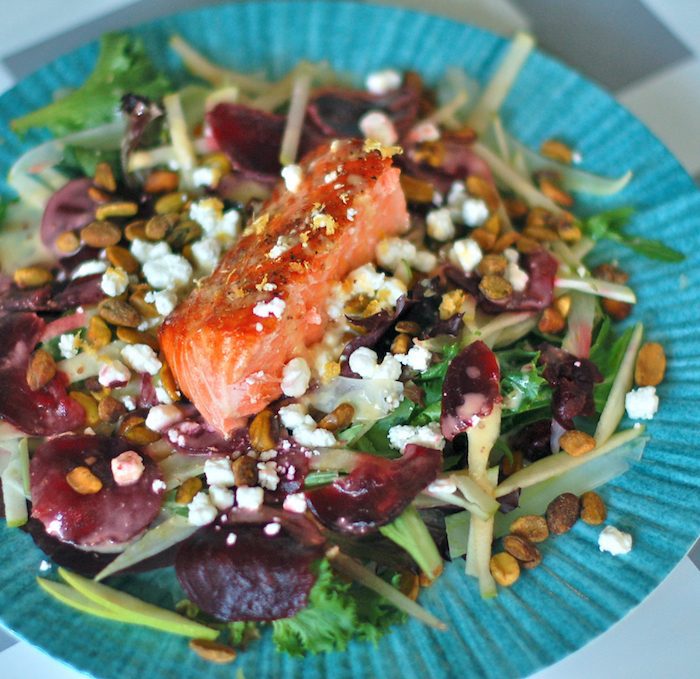 This Salmon Waldorf Salad combines mixed greens, ruby red beets, crisp fennel and green apple, crunchy pistachios, creamy goat cheese, and heart-healthy salmon with a citrus yogurt vinaigrette. A nutritious and delicious twist on the classic Waldorf salad. Get the gluten-free recipe via JessicaLevinson.com #waldorfsalad #healthysalads #salmonsalad Salmon Waldorf Salad Close Up