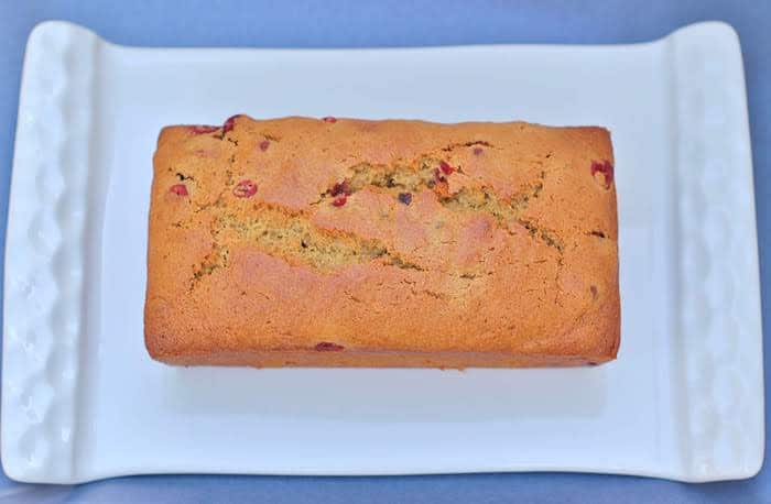 Cranberry Orange Bread | This whole-grain Cranberry Orange Bread will keep you healthy all winter long thanks to antioxidant-rich cranberries and vitamin C-rich oranges. Get this dairy-free and nut-free recipe @jlevinsonrd | #QuickBreadRecipe | #FallBaking | #QuickBreads Cranberry Orange Bread Loaf on Plate