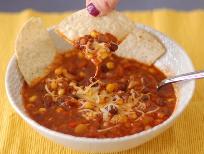 This gluten-free and dairy-free three bean vegetarian chili will warm you up and nourish you from the inside out throughout the cold days of winter! Get the full vegan recipe at JessicaLevinson.com #EasyVegetarianChili #EasyBeanChiliRecipe Three-Bean Vegetarian Chili with Dipped Tortilla Chip