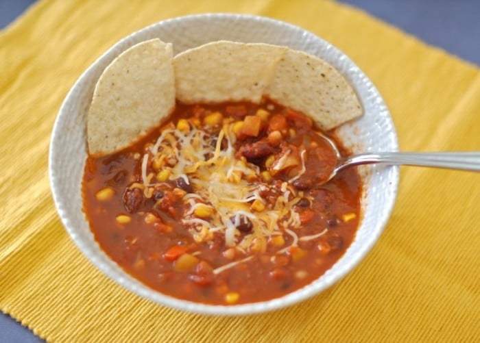 This gluten-free and dairy-free three bean vegetarian chili will warm you up and nourish you from the inside out throughout the cold days of winter! Get the full vegan recipe at JessicaLevinson.com #EasyVegetarianChili #EasyBeanChiliRecipe Three-Bean Vegetarian Chili Recipe in Bowl with Spoon