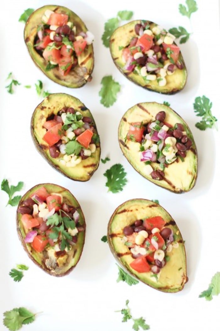 Grilled avocados are stuffed with a light and fresh mixture of corn, black beans, and tomatoes in this elegant yet simple appetizer, side dish, or entrée. Get the gluten-free and vegan recipe via JessicaLevinson.com #GrilledAvocados #StuffedAvocados Grilled Avocados on White Background