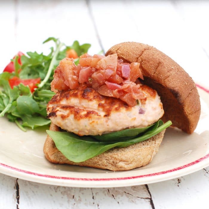 salmon burger with apple chutney Grilled Fresh Salmon Burgers on whole wheat bun with apple chutney on plate