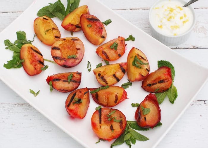 Grilled Stone Fruit with Honey Lemon Yogurt Sauce is a naturally delicious, low-calorie, vegetarian and gluten-free way to end to your summer BBQ. Get the recipe at JessicaLevinson.com | #GrilledFruit #StoneFruitRecipes Grilled Stone Fruit on White Platter