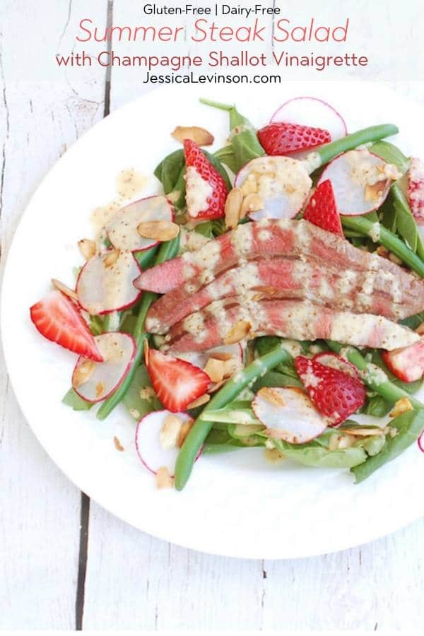 Umami-rich grilled flank steak tops a bed of baby spinach, crisp green beans, and sweet strawberries in this light summer steak salad drizzled with a sparkling, tangy Champagne shallot vinaigrette. via JessicaLevinson.com | #steaksaladrecipe #summersaladrecipe Summer Steak Salad Recipe with Text Overlay