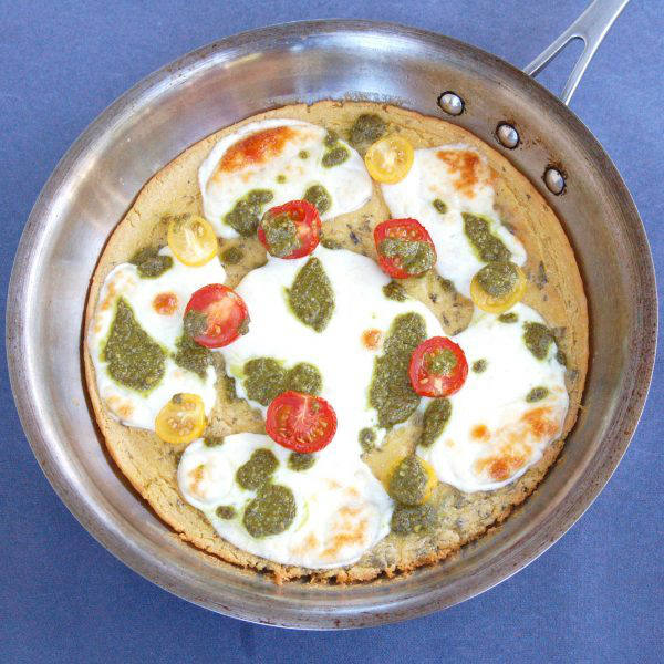 Farinata with Tomato, Mozzarella, & Pesto Drizzle | A chickpea flour crust is topped with tomatoes, mozzarella, and basil pesto in this easy, gluten-free, vegetarian twist on traditional Italian farinata | Get the recipe via JessicaLevinson.com #farinatarecipe #ChickpeaFlour #ItalianRecipes Overhead of Farinata with Tomato Mozzarella and Pesto