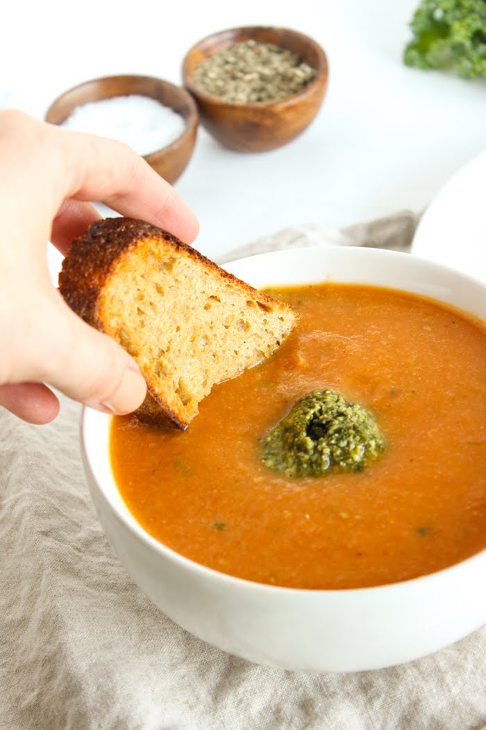 Warm up this fall and winter with a bowl of tomato white bean soup topped off with a dollop of kale pesto. Gluten free, vegetarian, and vegan-friendly. Recipe via JessicaLevison.com #TomatoSoupRecipe #VegetarianSoup Tomato White Bean Soup with Bread