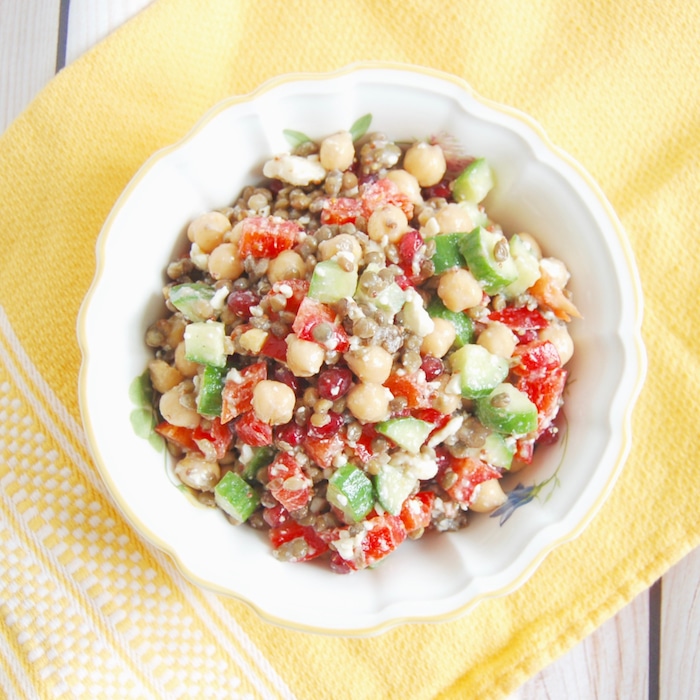 Lentil Chickpea Vegetable Salad with Feta | Protein and fiber-rich lentils and chickpeas, crunchy bell peppers and Persian cucumbers, sweet pomegranate seeds, and salty feta cheese are tossed together in a lemony maple-mustard vinaigrette for a kid-friendly and adult approved lunchbox salad. Get this gluten-free, nut-free, vegetarian, and vegan-friendly recipe via JessicaLevinson.com #LentilSaladRecipe #VegetarianLentilSalad Lentil Chickpea Salad in Bowl