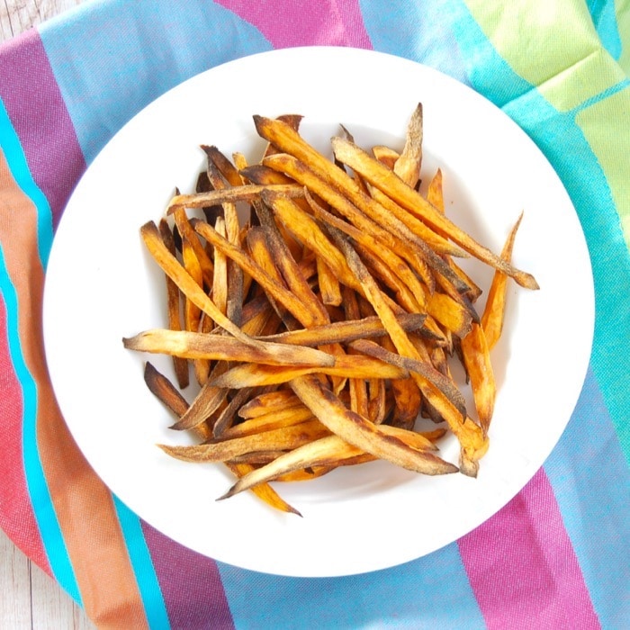 Crispy baked sweet potato fries are easy to make, kid-friendly, and delicious. The perfect side dish for any weeknight family dinner! Get the recipe at JessicaLevinson.com #HealthySweetPotatoFries #BakedSweetPotatoFriesRecipe Crispy Baked Sweet Potato Fries on White Plate