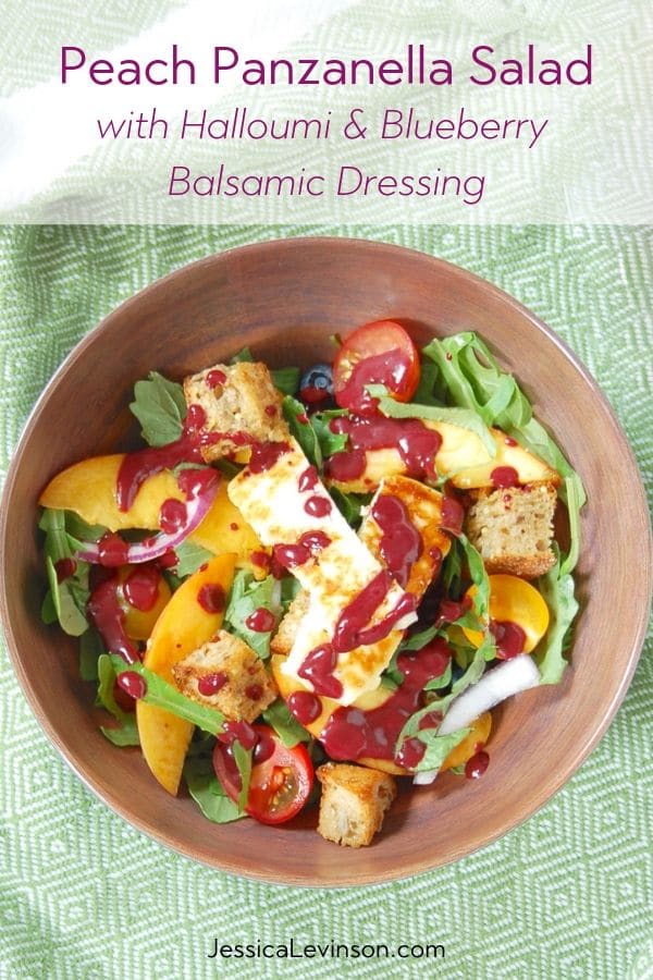 Juicy peaches, ripe tomatoes, briny halloumi cheese, and crunchy rustic bread come together in this Peach Panzanella Salad, a twist on a classic Tuscan summer dish. Get the quick and easy, vegetarian summer recipe at JessicaLevinson.com | #vegetarian #peaches #saladrecipes #summerrecipes peach panzanella salad topped with blueberry balsamic dressing