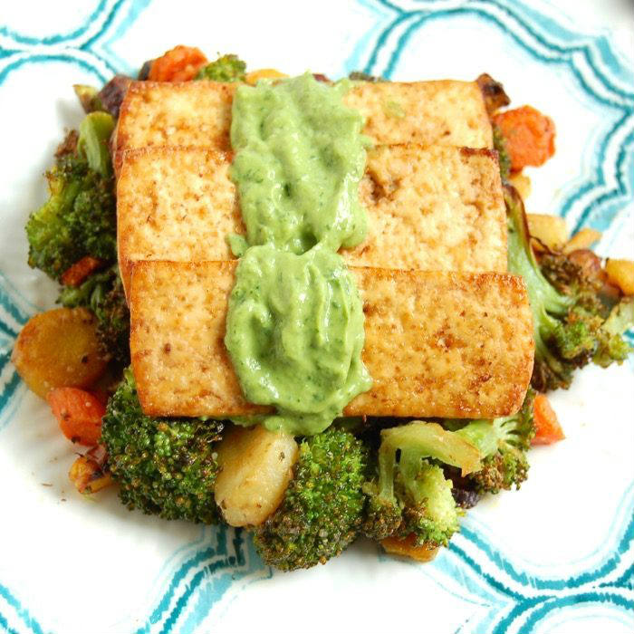 Tofu with cilantro avocado cream sauce Close Up of broiled tofu over roasted broccoli, carrots, and parsnips topped with avocado sauce