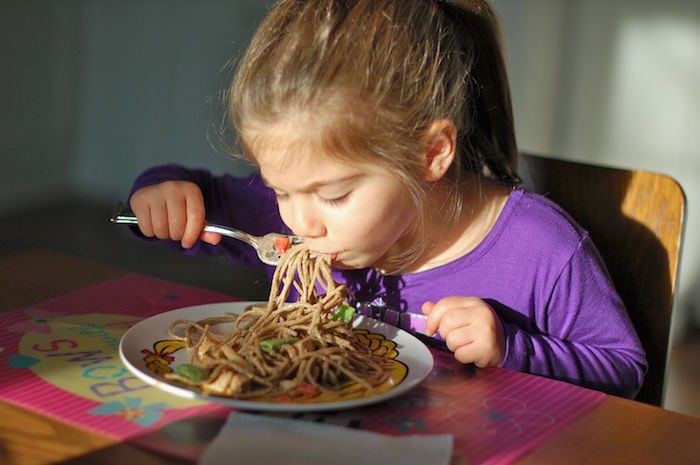 Sabrina at 3 years old eating peanut soba noodles. little girl eating noodles with vegetables