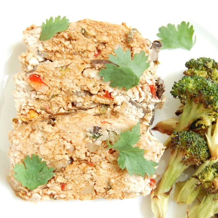 A twist on classic meatloaf, this Asian-style turkey meatloaf is loaded with vegetables, herbs and spices, and topped with a sweet and spicy glaze. close up of Asian-style turkey meatloaf on dinner plate