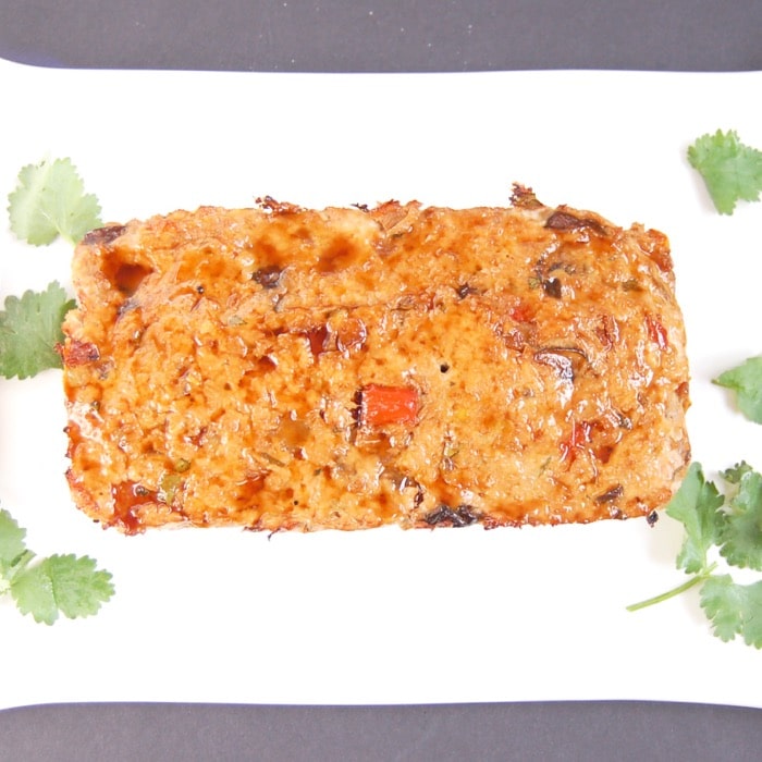 A twist on classic meatloaf, this Asian-style turkey meatloaf is loaded with vegetables, herbs and spices, and topped with a sweet and spicy glaze. Asian style turkey meatloaf on platter