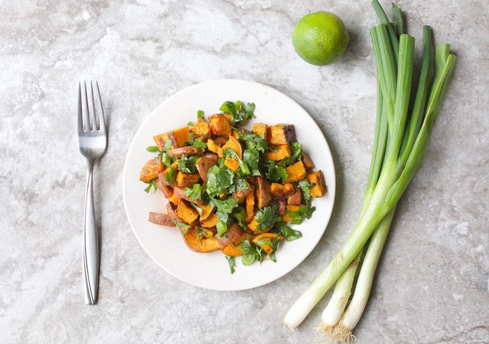 Lighten up classic potato salad with roasted sweet potato salad tossed with cilantro, scallions, and a honey lime vinaigrette via JessicaLevinson.com #SweetPotatoSalad #HealthyPotatoSalad Roasted Sweet Potato Salad on Plate with Lime and Scallions